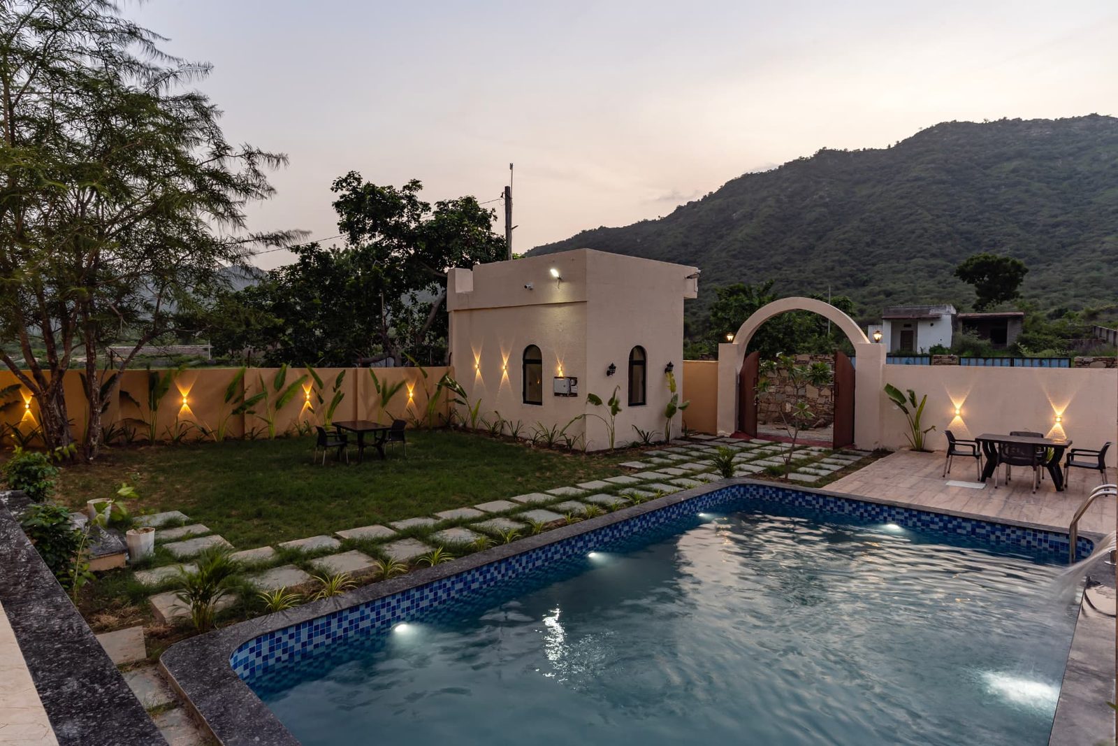Swimming pool, lawn and seating area with hill views at Alora Woods Villa