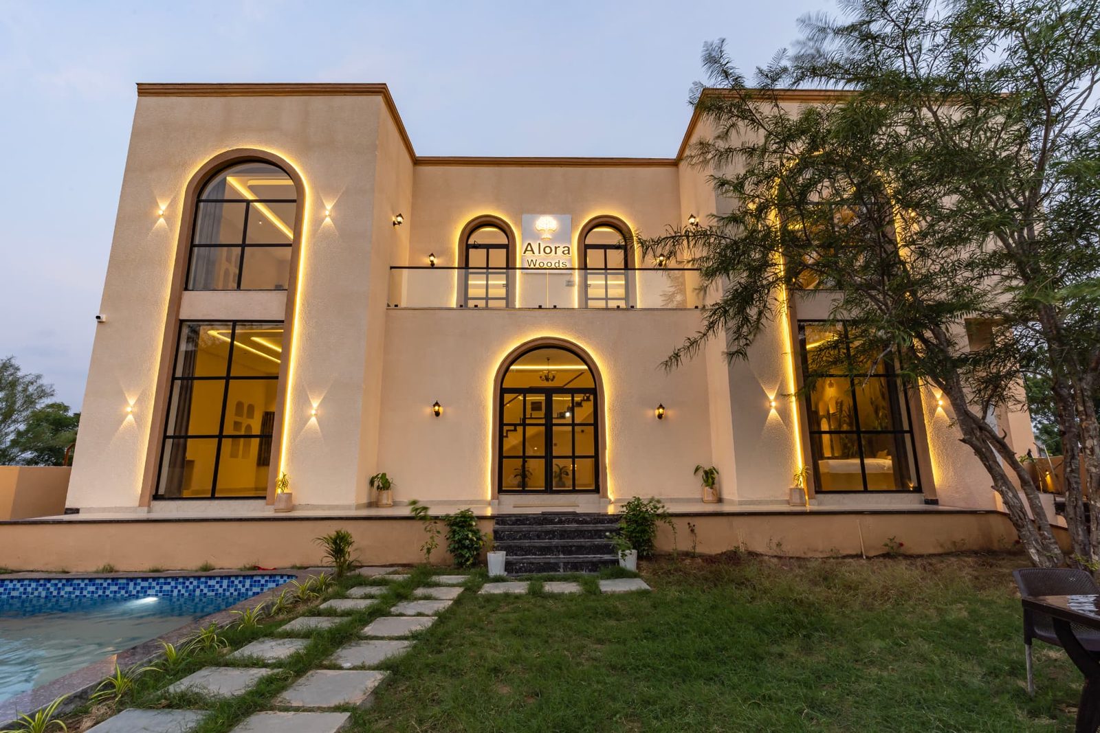 Alora Woods Villa exterior lit up at dusk beside the pool